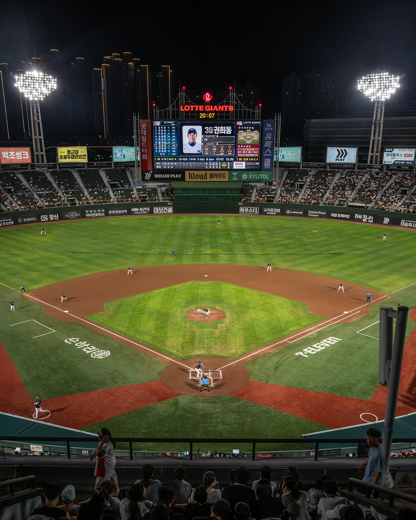 Baseball - A night baseball game unfolds under bright stadium lights, with players spread across the field and spectators watching from the stands. - #Busan #LotteGians #Baseball #Sajik #NightGame