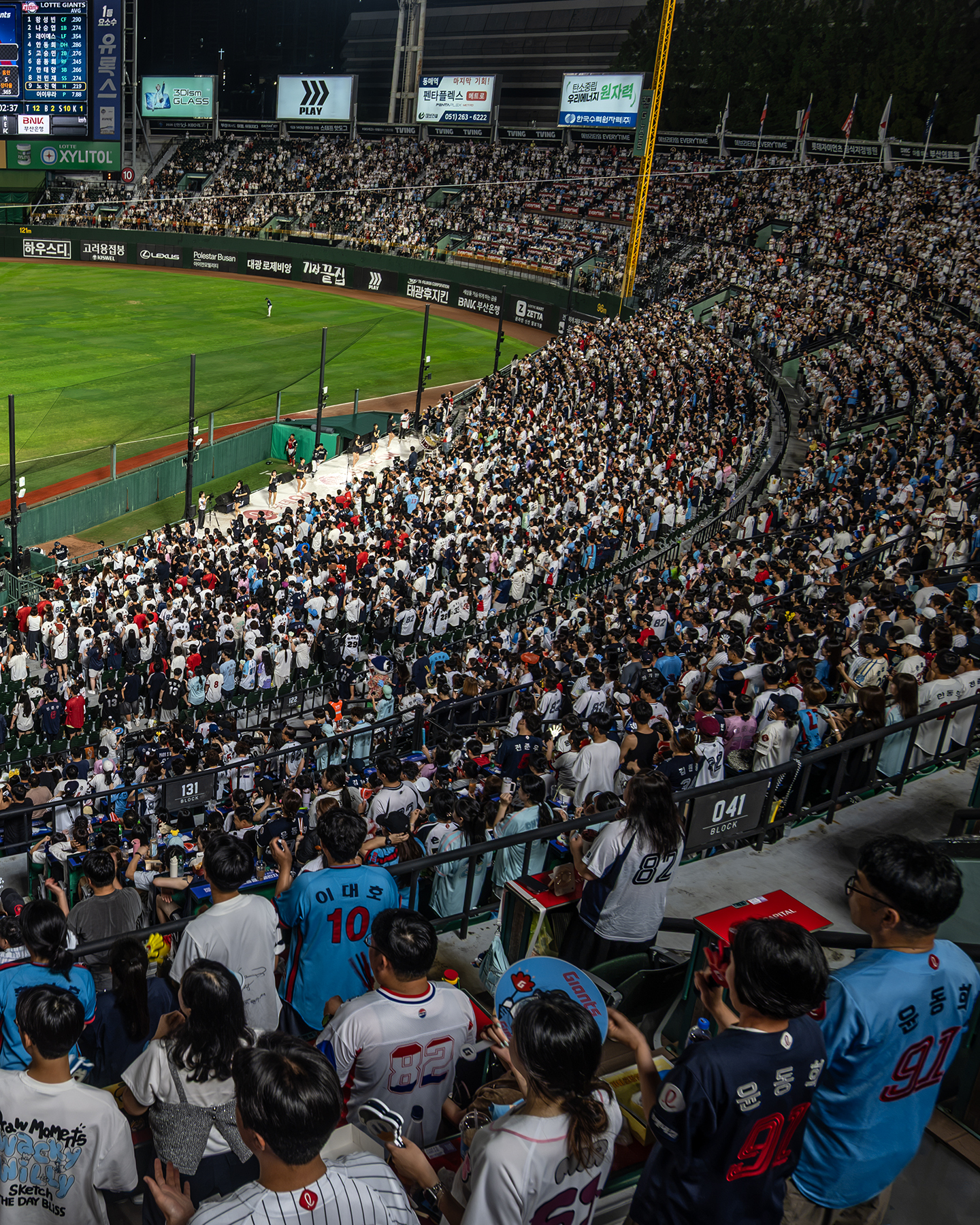 Baseball - A packed baseball stadium crowd watches from steep stands under bright night lights beside the green outfield. - #Busan #LotteGians #Baseball #Sajik #NightGame