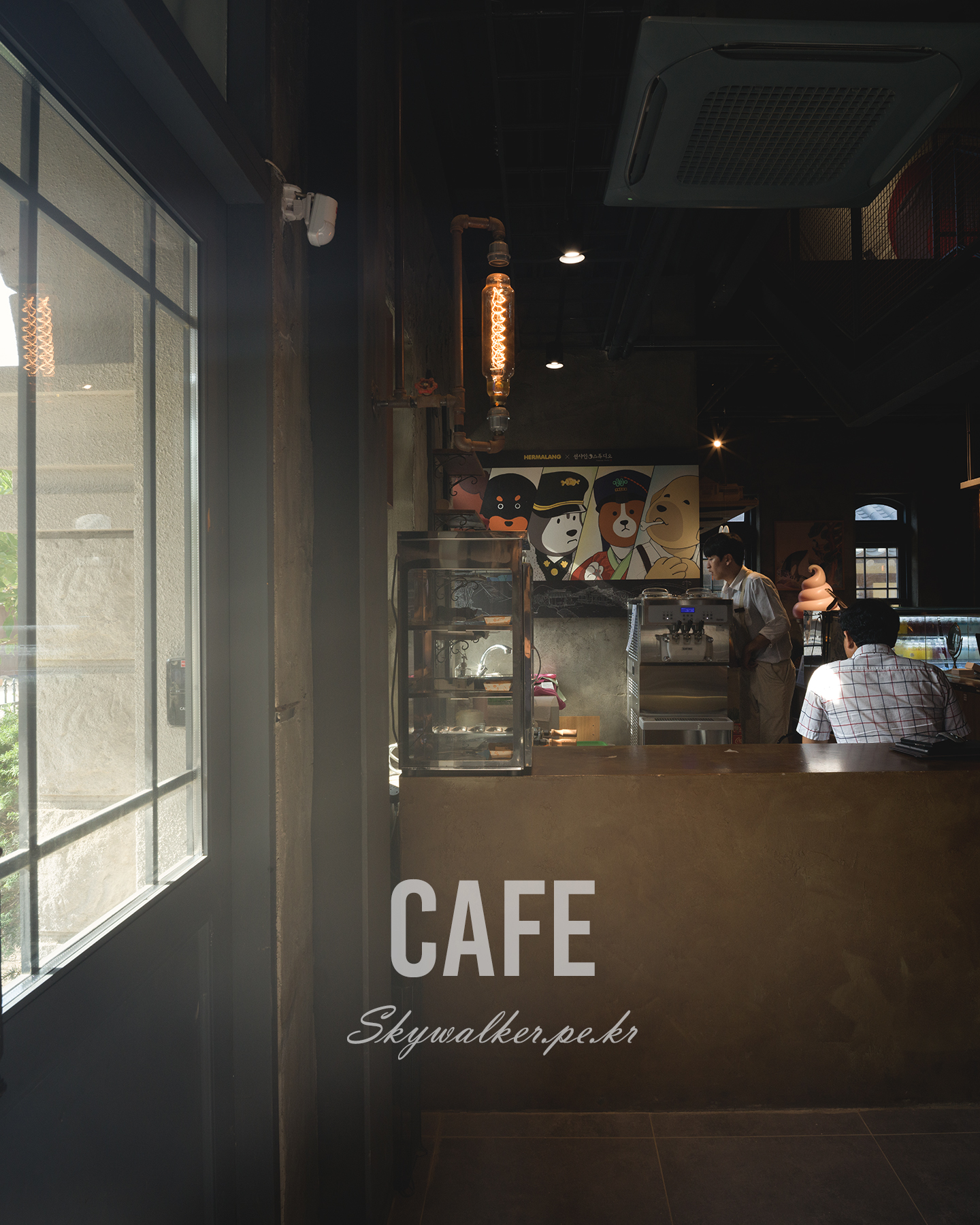 Cafe - A dim cafe interior with a sunlit window, glowing Edison bulb, counter, and patrons beneath a playful wall mural. - #SunshineStudio #NonsanSunshineStudio #SunshineStudioCafe #Nonsan #Cafe #KoreanCafe #RetroCafe #VintageCafe #CafeInterior #CafePhotography