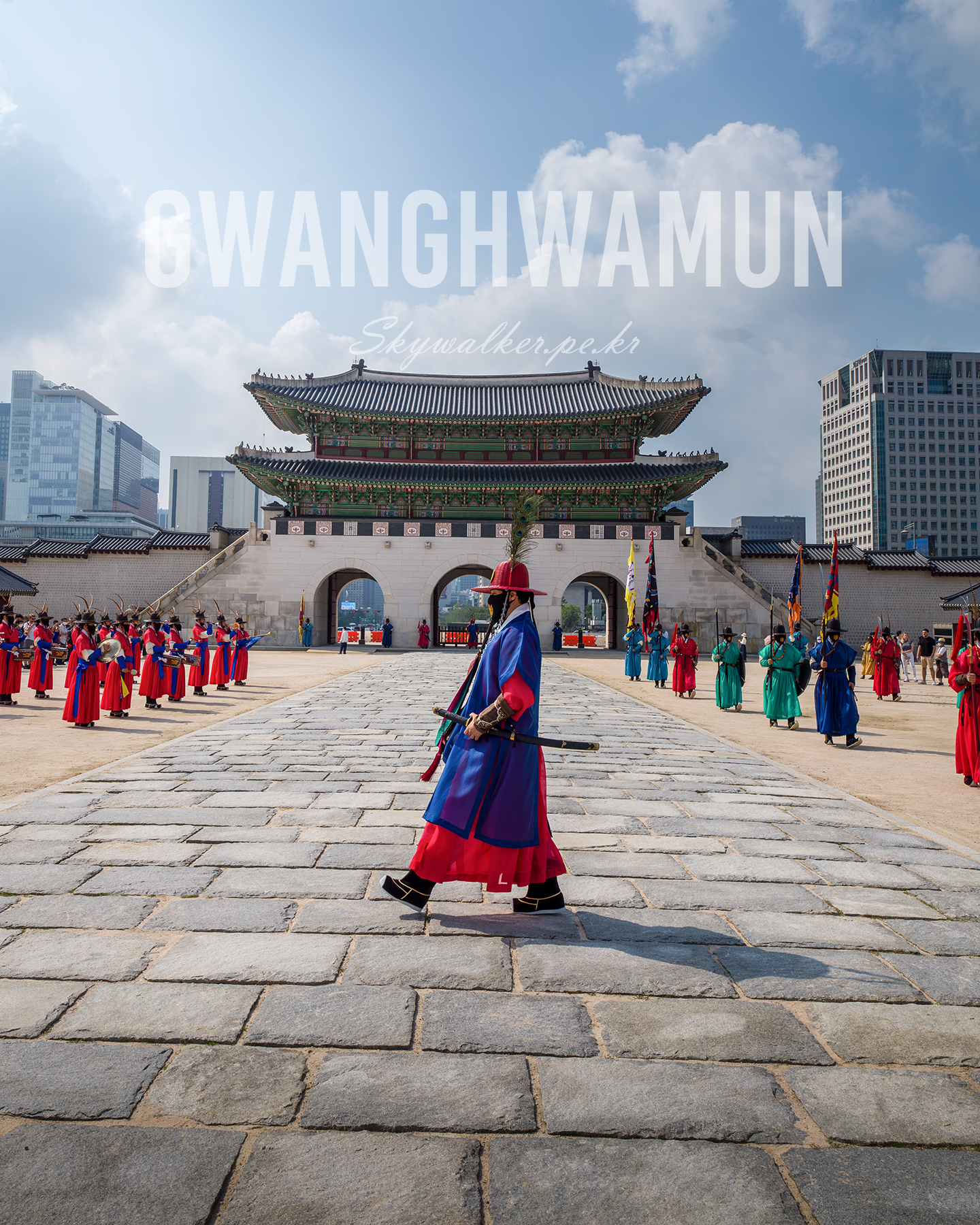 Gwanghwamun - Ceremonial guards in vivid traditional uniforms gather before an ornate palace gate under a bright, cloud-filled sky. - #Gwanghwamun #CeremonialGuards #PalaceGate #TraditionalUniforms #KoreanArchitecture #CulturalHeritage #StonePath #BlueSky #Clouds #TravelPhotography