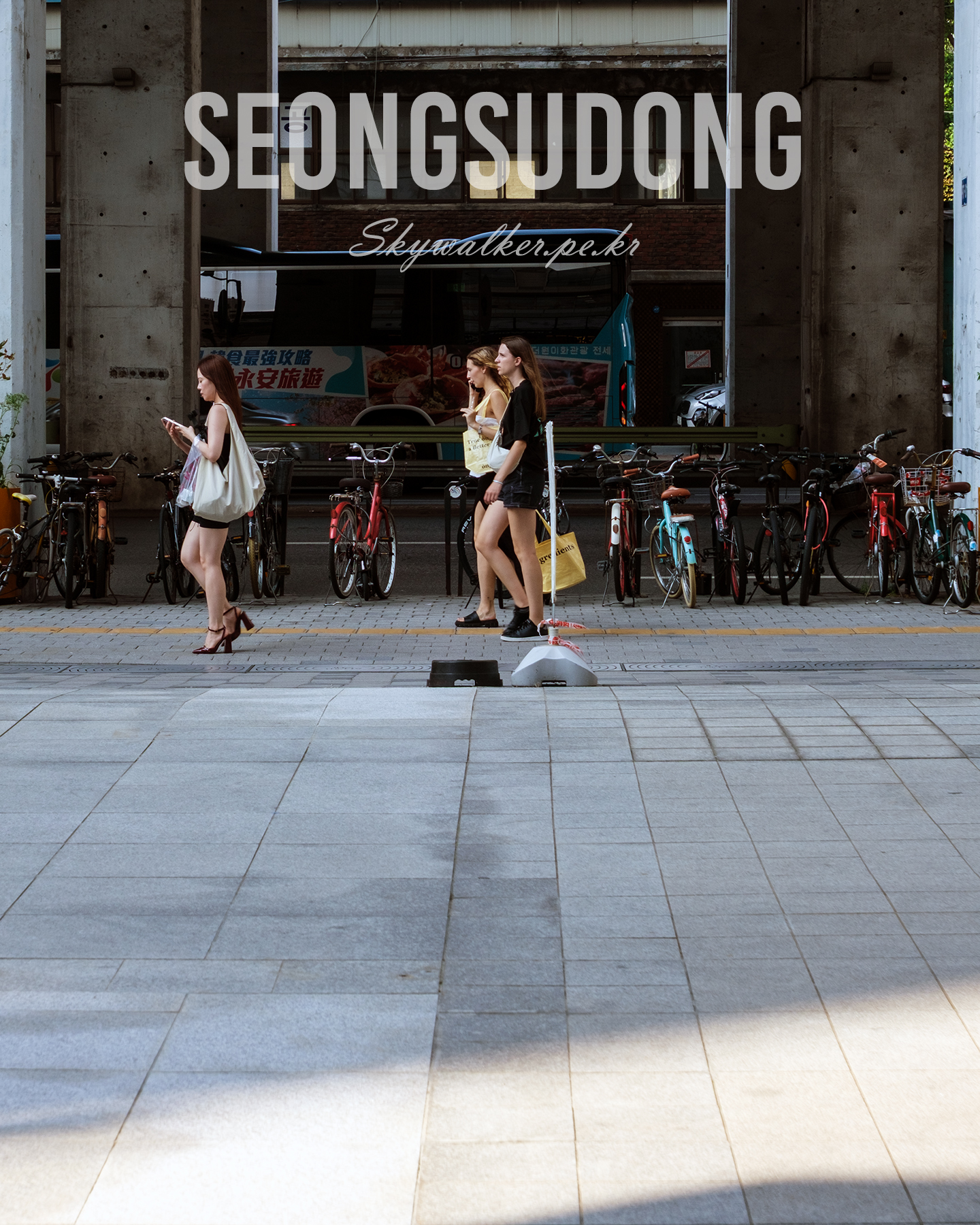 Seongsudong - Pedestrians pass parked bicycles beneath tall concrete columns, with a bus and brick facade in the shaded urban background. - #StreetPhotography #UrbanScene #Pedestrians #Bicycles #ConcreteColumns #CityWalk #Shadows #Sidewalk #Bus #Architecture