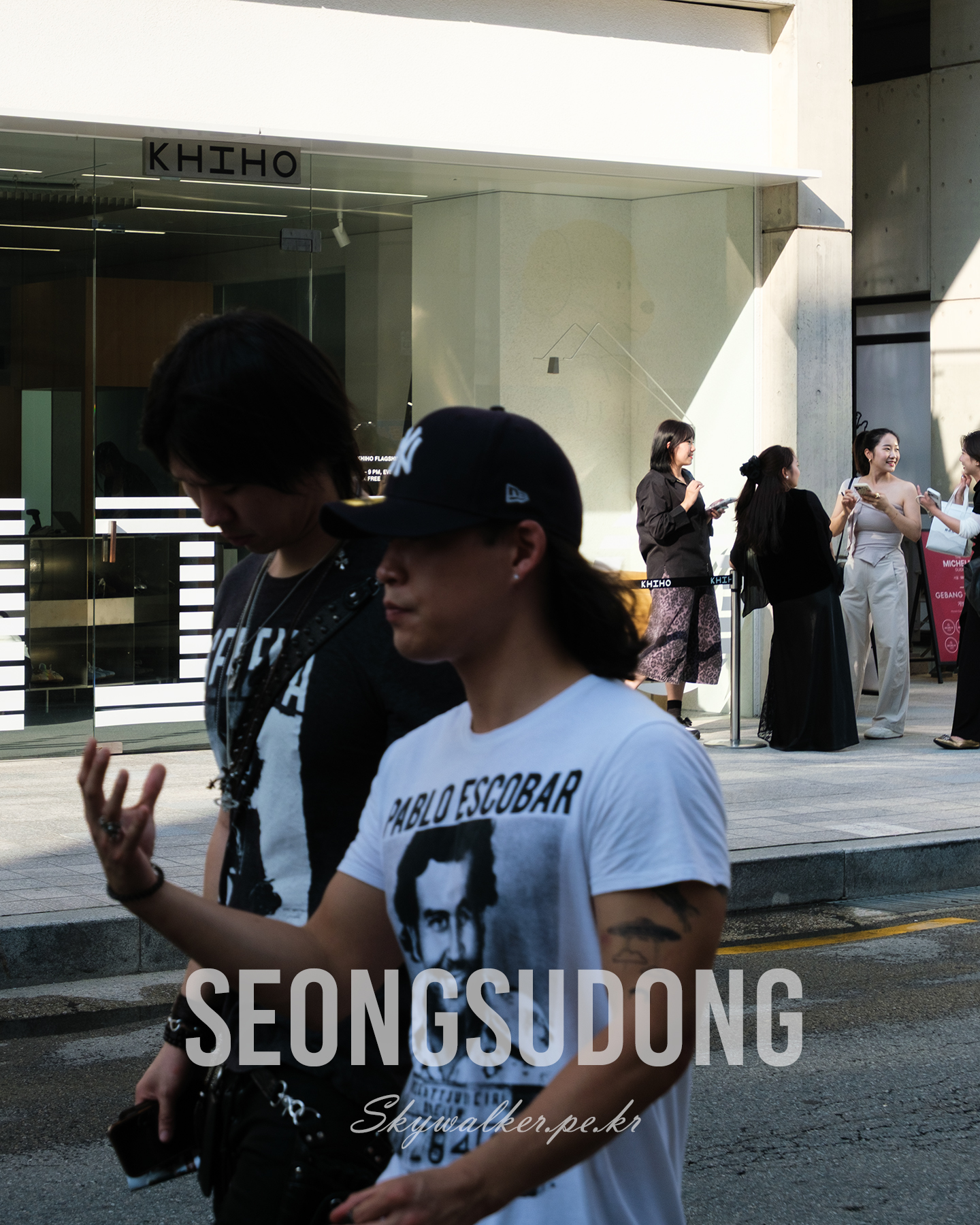 Seongsudong - Pedestrians pass a glass storefront as warm sunlight and deep shadows shape a lively urban street scene. - #StreetPhotography #UrbanScene #Seongsudong #CityLife #Sunlight #Shadows #Storefront #Pedestrians #Candid #Architecture