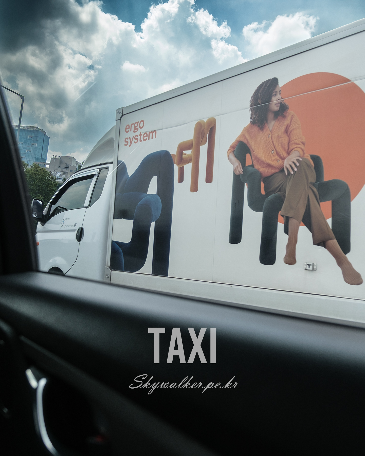 Taxi - Seen through a taxi window, a white advertising truck passes beneath dramatic clouds beside city buildings. - #TaxiView #StreetPhotography #UrbanScene #Truck #Advertising #WindowView #Cityscape #Clouds #Daylight #Composition