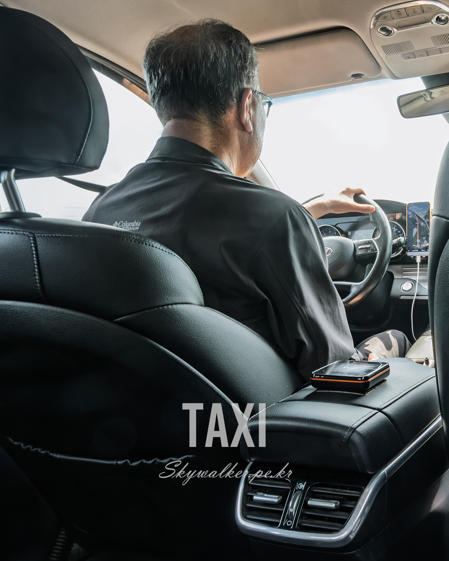Taxi - A driver is seen from the back seat inside a taxi, holding the wheel as bright daylight floods the windshield. - #Taxi #Driver #CarInterior #BackSeatView #UrbanTravel #Navigation #Daylight #StreetPhotography #Transport #Candid