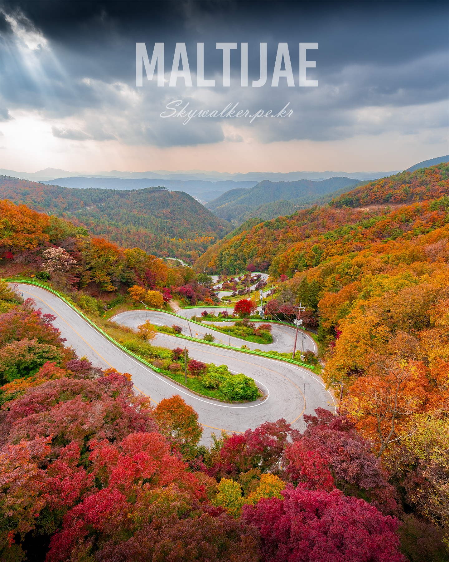 Maltijae - A winding mountain road curves through vivid autumn forest beneath layered storm clouds and soft distant hills. - #Maltijae #AutumnForest #MountainRoad #WindingRoad #FallColors #LandscapePhotography #DramaticSky #ScenicView #MountainLandscape #NaturePhotography