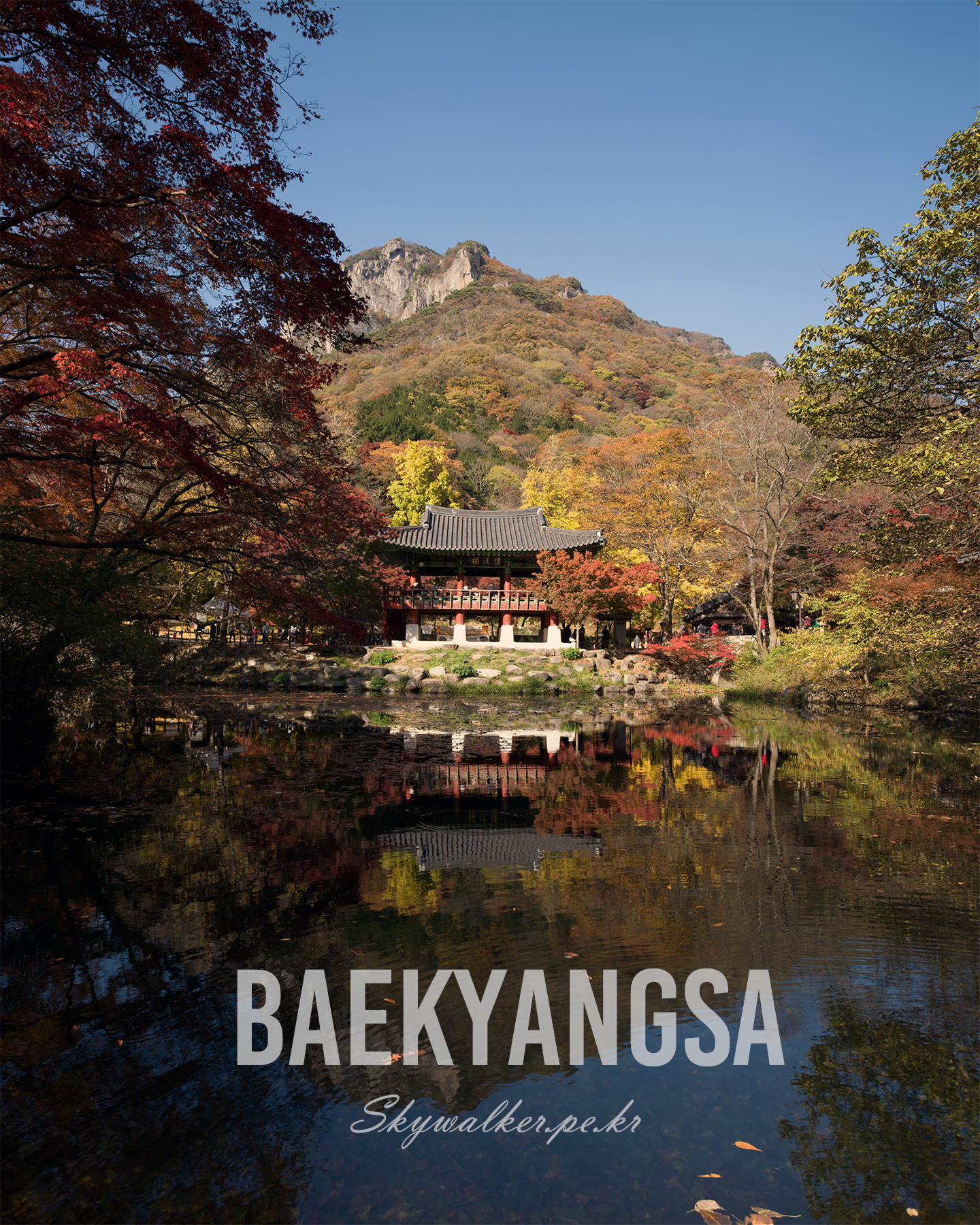 Baekyangsa - A traditional pavilion reflects in a calm pond beneath autumn foliage and rocky mountains under a clear blue sky. - #Baekyangsa #AutumnFoliage #Pavilion #Reflection #MountainView #TempleScenery #KoreanArchitecture #Pond #LandscapePhotography #ClearSky