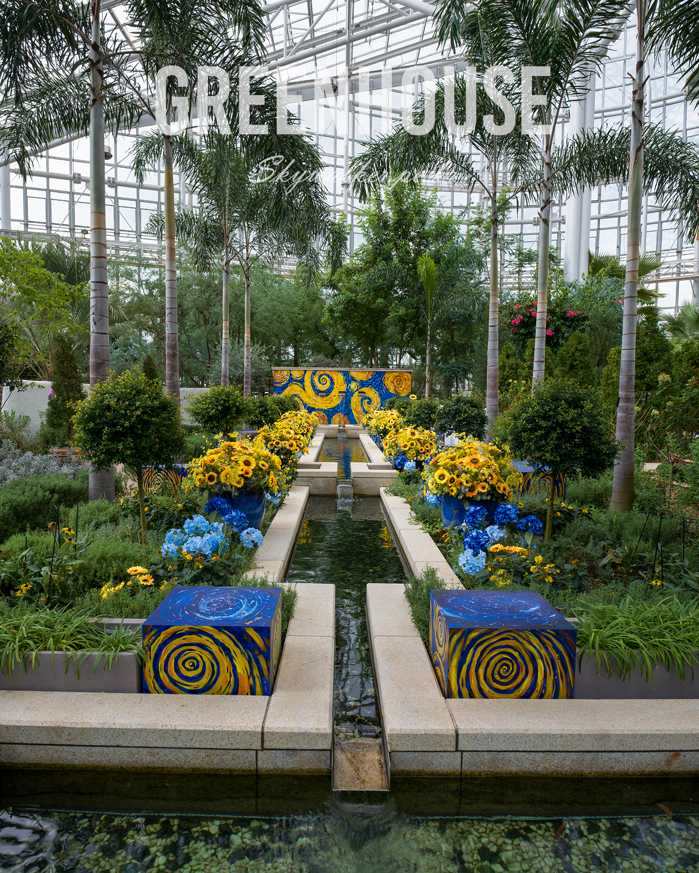 Greenhouse - A symmetrical greenhouse garden frames a narrow water channel with palms, yellow flowers, and blue-and-gold painted accents under soft glass-roof light. - #Greenhouse #BotanicalGarden #IndoorGarden #PalmTrees #WaterFeature #FloralDisplay #GardenDesign #GlassRoof #Symmetry #TropicalPlant