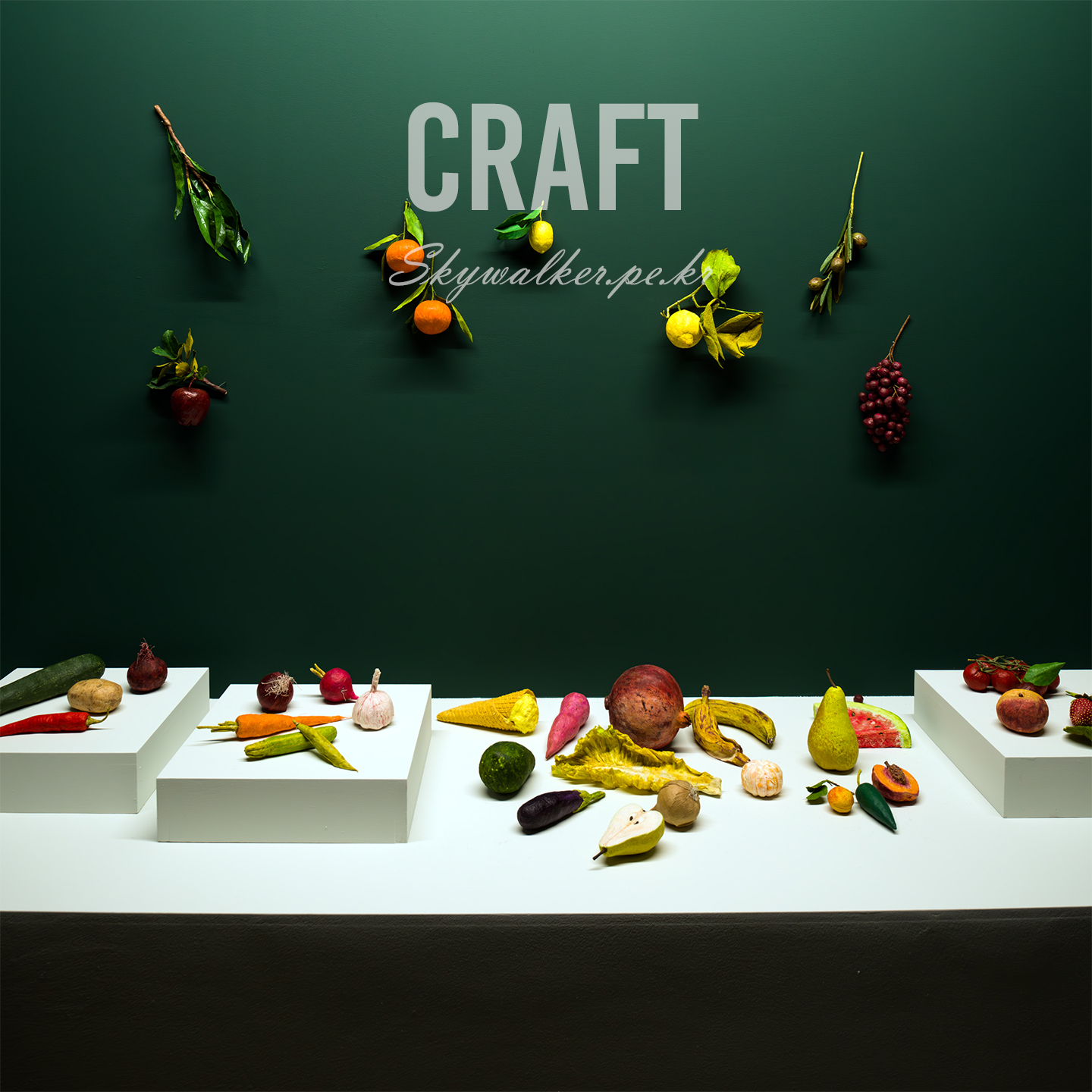 Craft - A staged still life of fruits and vegetables rests on white plinths against a dark green wall with hanging branches and bold CRAFT text. - #stilllife #fruit #vegetables #foodphotography #greenwall #studio #composition #plinths #craft #minimal