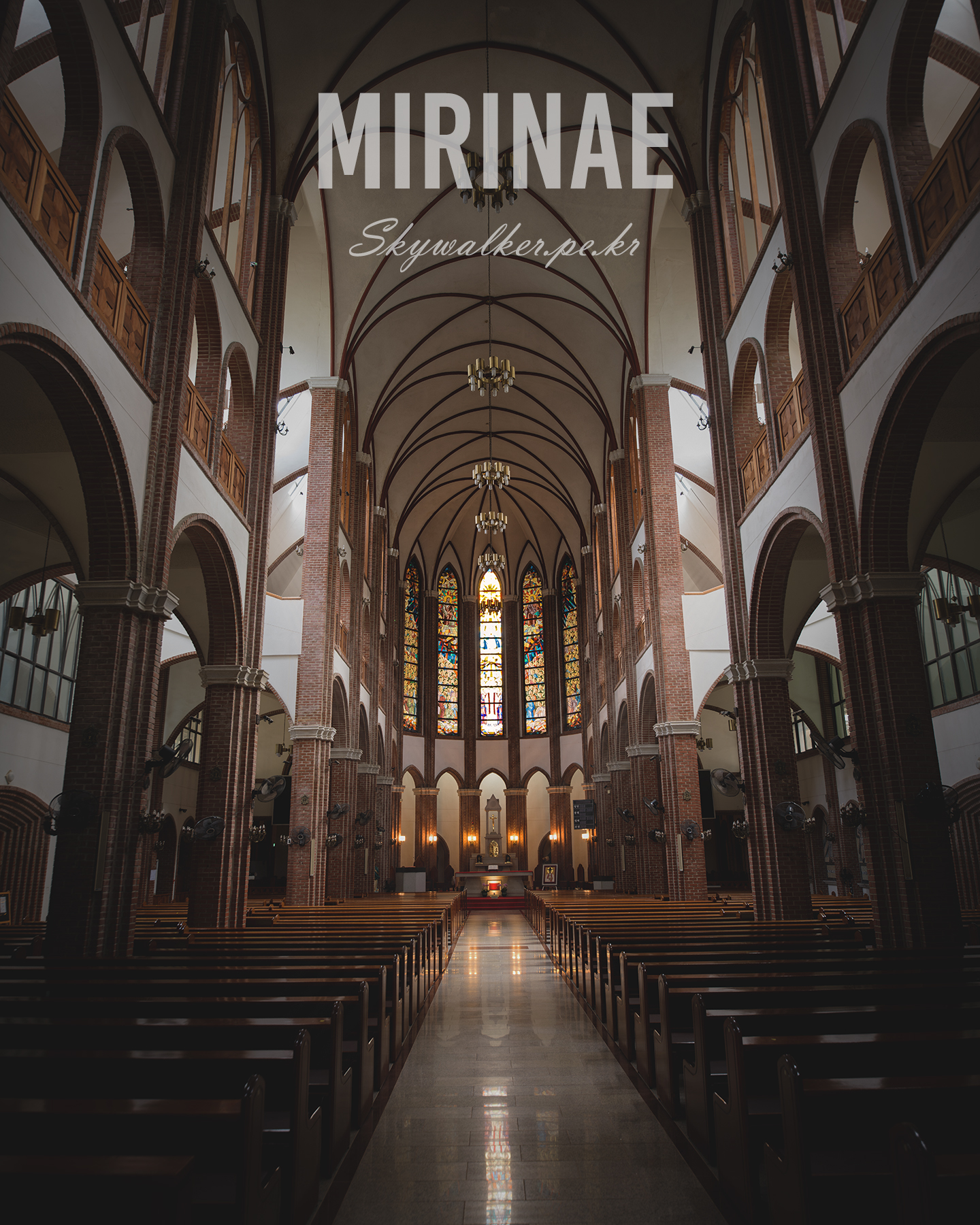Mirinae - A vaulted brick church nave leads between dark wooden pews toward stained glass windows glowing in soft interior light. - #ChurchInterior #GothicArchitecture #BrickArches #StainedGlass #VaultedCeiling #Symmetry #Nave #Pews #SacredSpace #InteriorPhotography